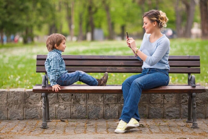 Mamãe tecnológica tirando foto do filho no parque